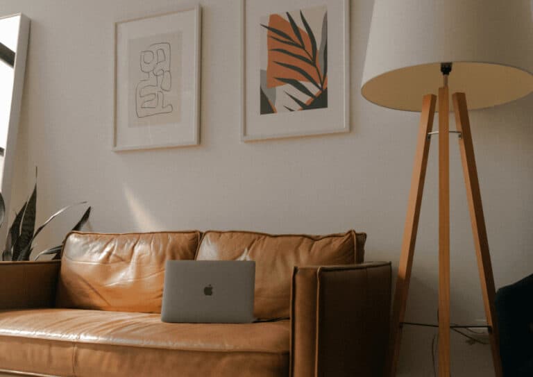 A Macbook is on the leather couch