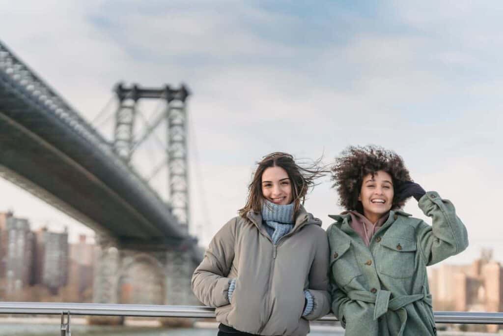 two women in winter coats smiling outside