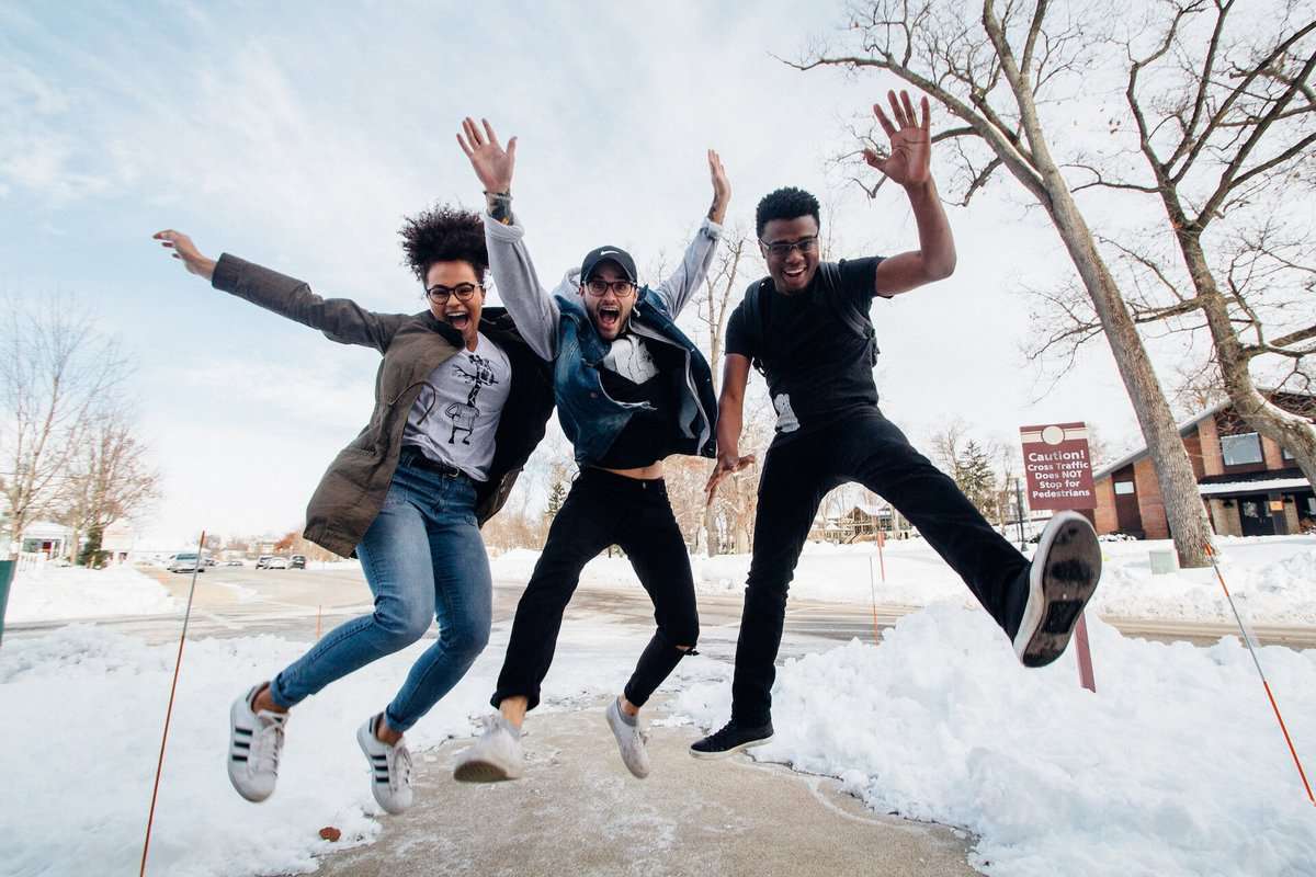 three people are jumping outside in winter