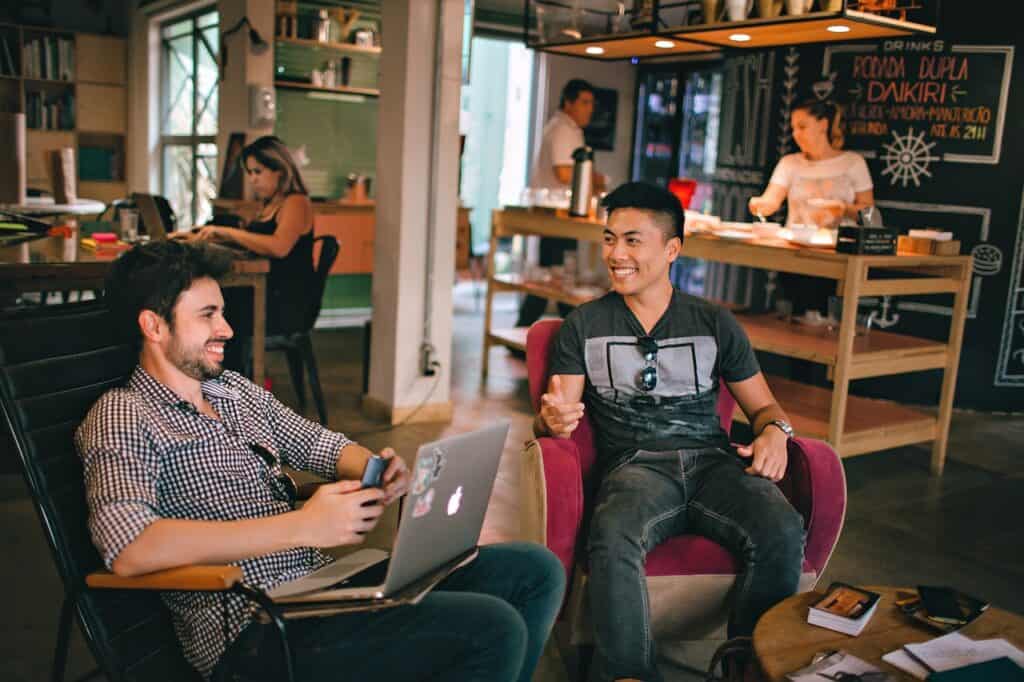 two men chatting in a cafe with people in the background