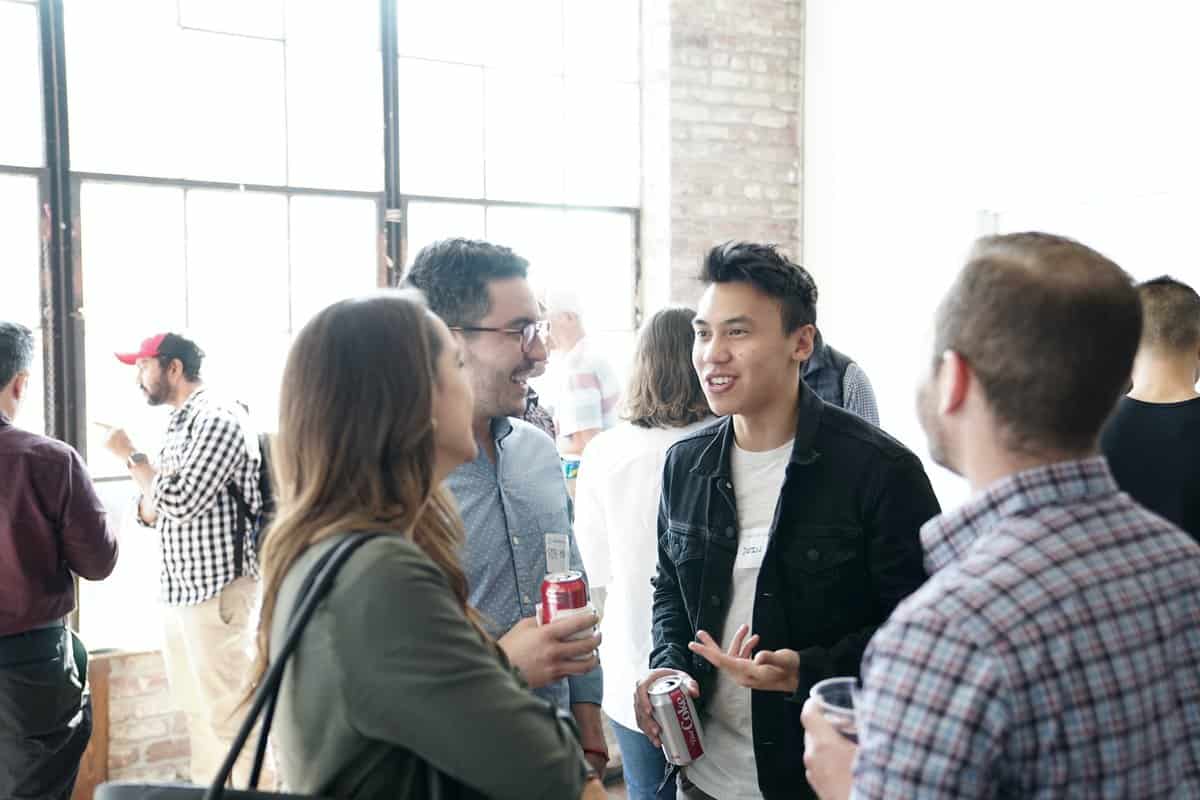 group of young individuals standing in a room chatting