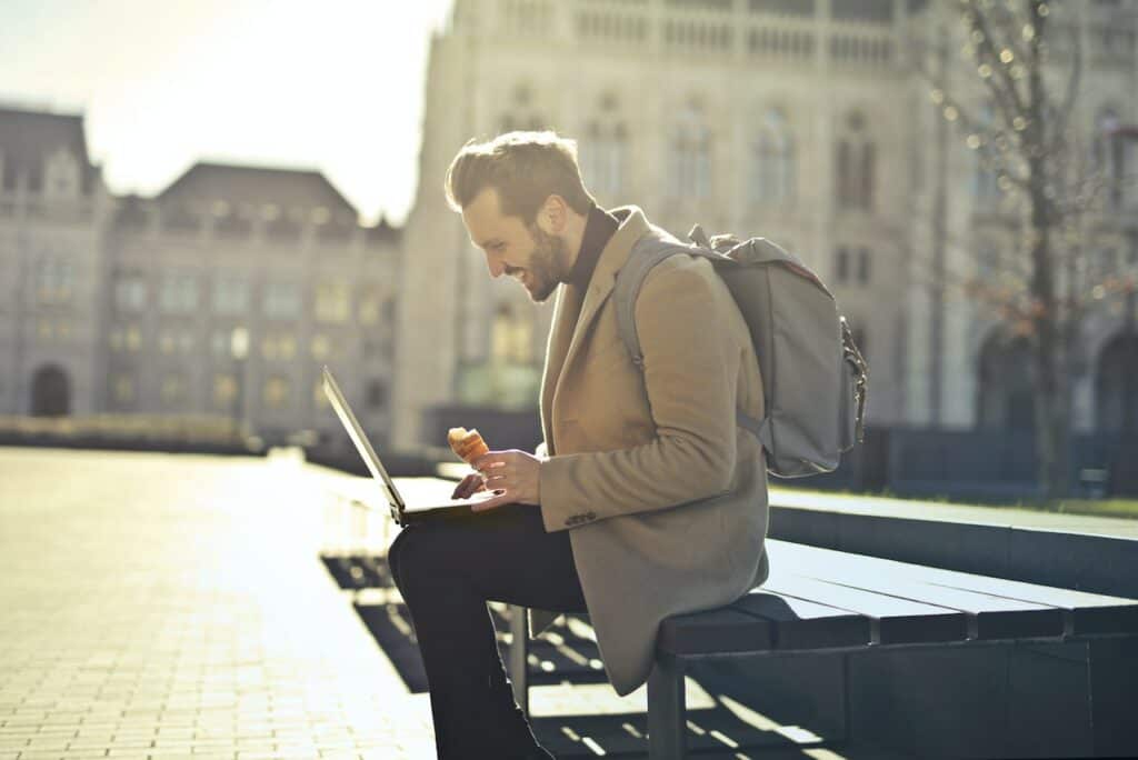 man sitting in the part with his backpack and laptop