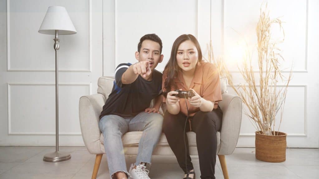 Boy and girl playing a game with a game console on the sofa