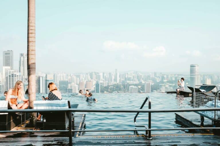 Shared pool area with a view of the city with people swimming and talking.