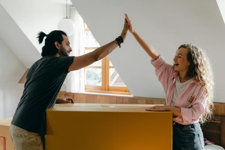 A happy couple giving each other a high-five while unpacking in their new home