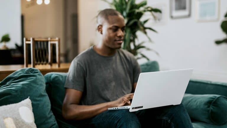 man in grey shirt using laptop on sofa