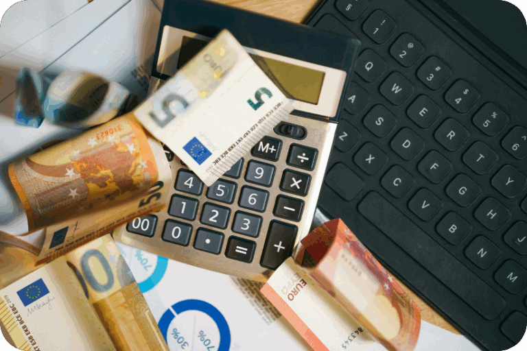 Euro bills on a calculator and keyboard representing budgeting and insurance costs