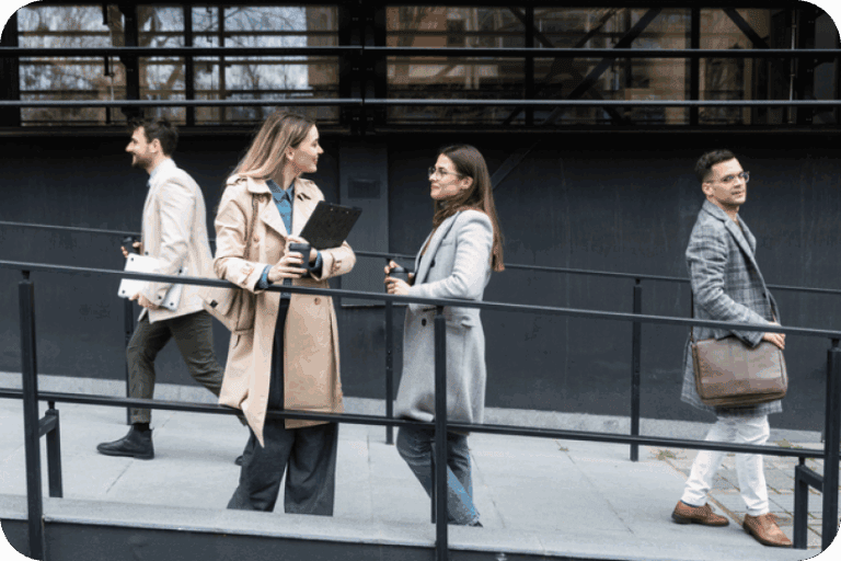 Group of expats walking with paperwork and coffee outside a building
