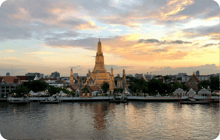 Sunset over Wat Arun temple and city skyline reflecting on the Chao Phraya River in Bangkok, Thailand