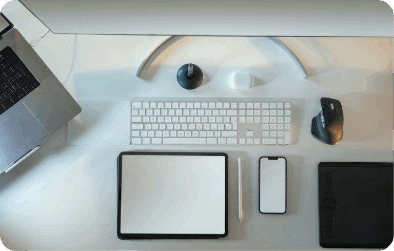 Top view of modern desk setup with laptop, tablet, phone, keyboard, and accessories