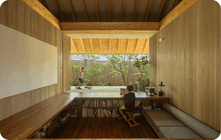 Child reading in a wooden room that opens to a garden patio