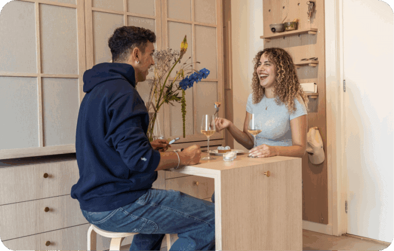 Couple sharing a meal in a compact, warm-toned studio